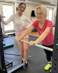 Trenerka personalna Body Movement Mokotów pokazuje podopiecznej ćwiczenie podczas treningu indywidualnego.

